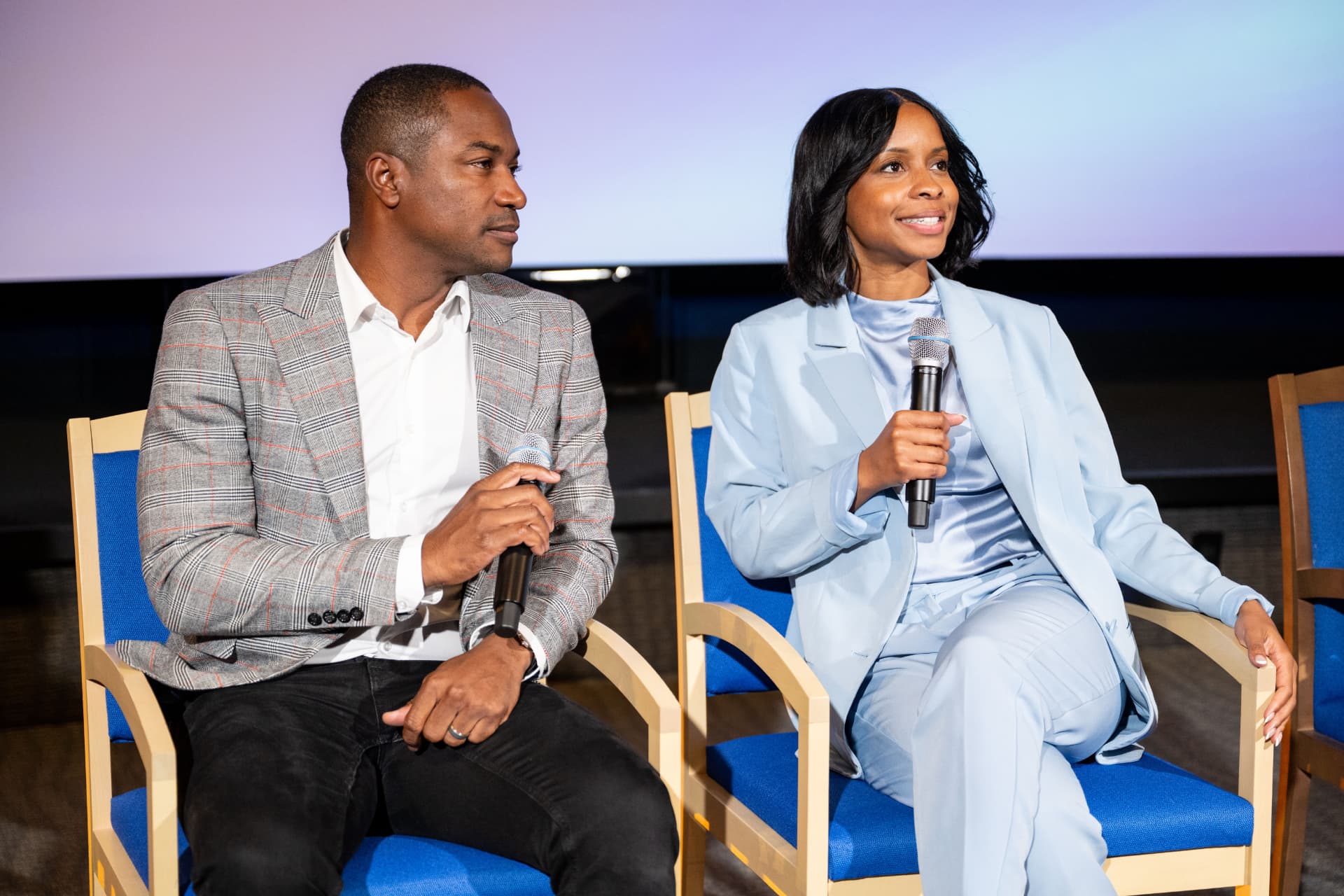 Two panelists answering questions with handheld microphones